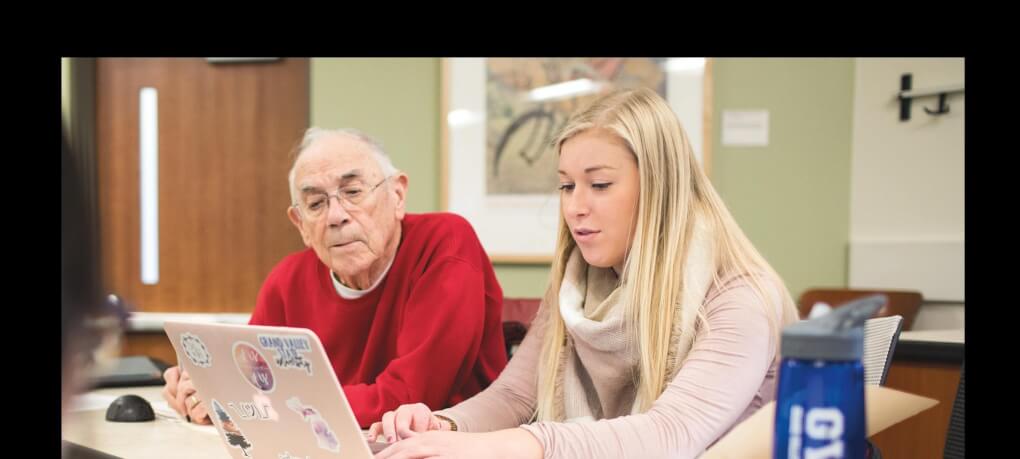 A student sits with a retiree during class